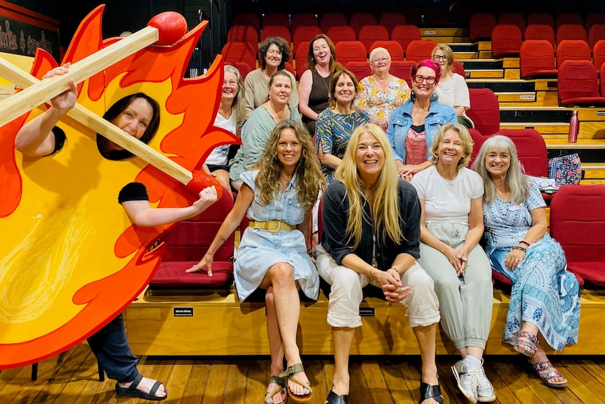 A group of women are sitting on chairs in a hall.