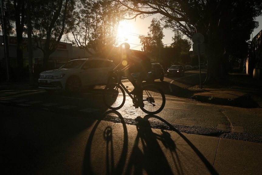 a woman riding a bike with the sun setting behind her