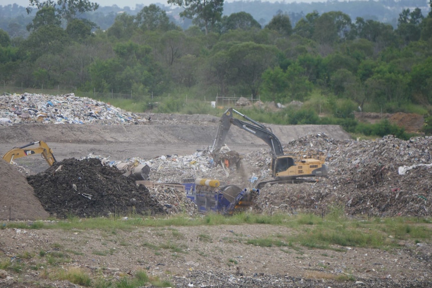 Two heavy loaders move construction waste at a landfill at New Chum, Ipswich