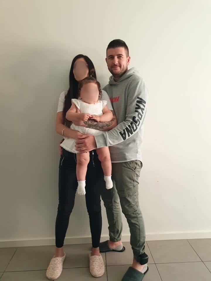 Man wearing grey hoodie standing with woman holding baby girl