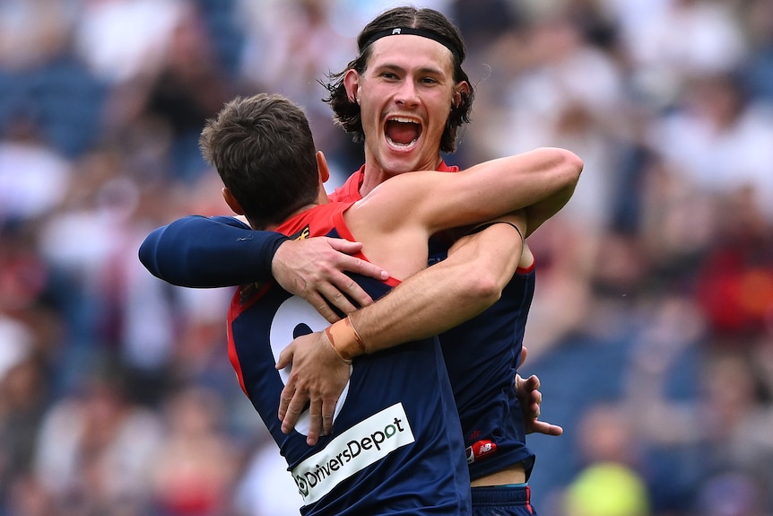Two Melbourne AFL players embrace as they celebrate a goal against St Kilda.