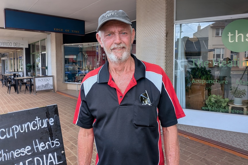 Man with grey beard in polo shirt on footpath in rural town of Dorrigo
