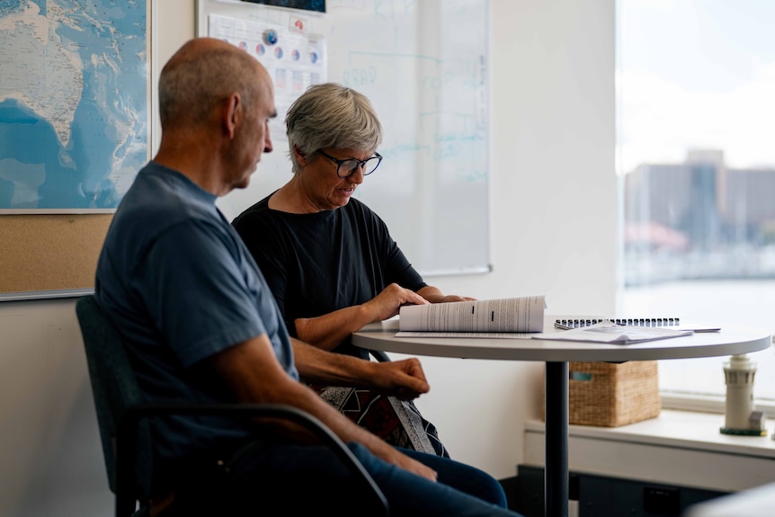 Man and woman pose for photo at a science office building by the water