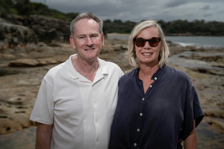 A couple stand near the ocean.