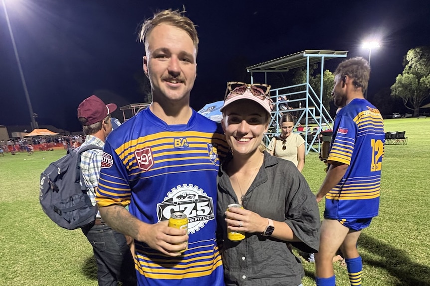 Man in football jersey stands with woman on field after the game. 