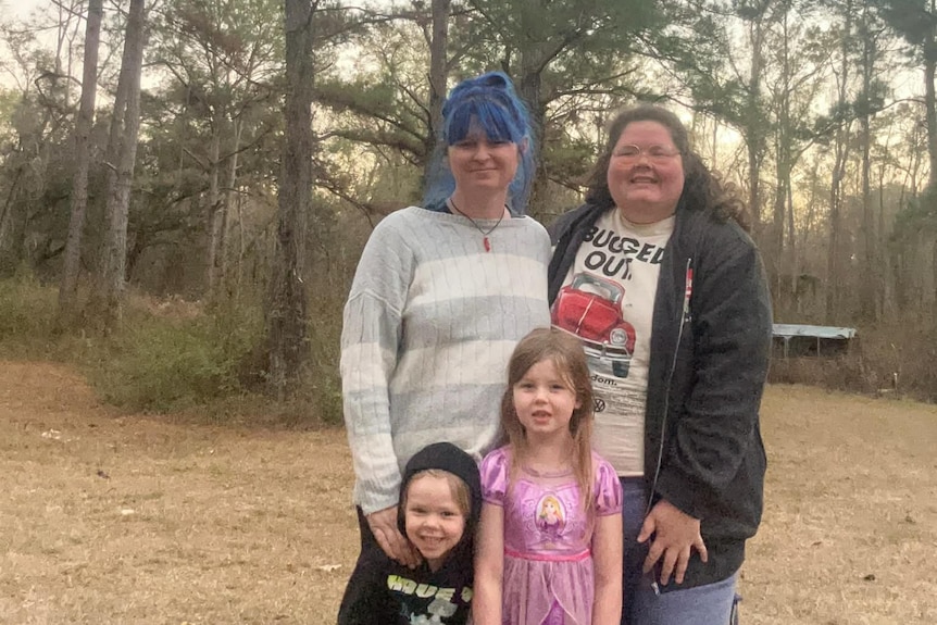 Kiley smiles with her wife and two young children in nature.