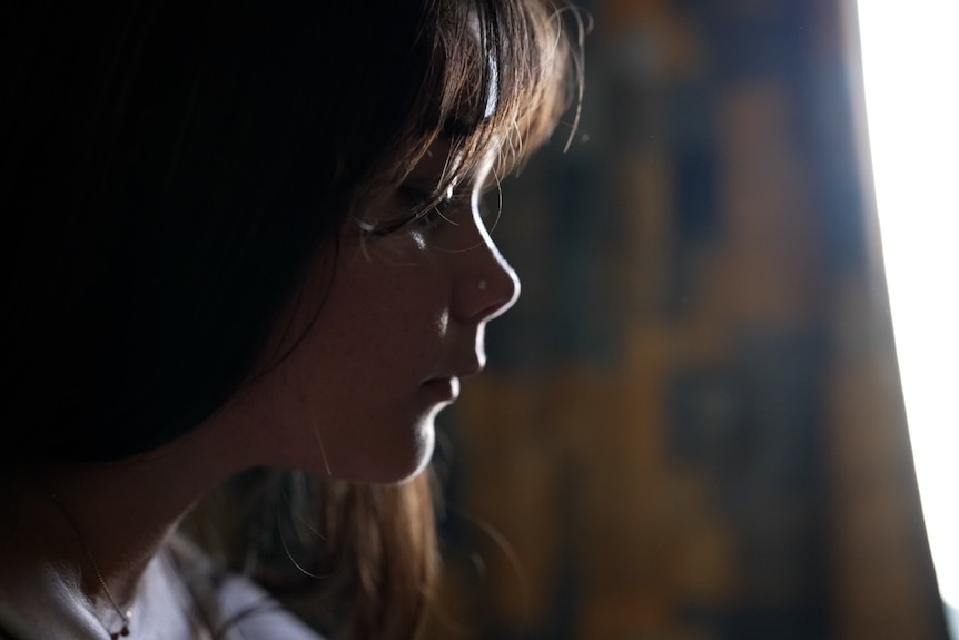 A close up of a young girl in the dark. 