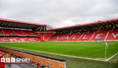 Charlton play at The Valley, seen here with empty stands featuring red seats with large white letters spelling out CAFC at one end and The Valley down one side.