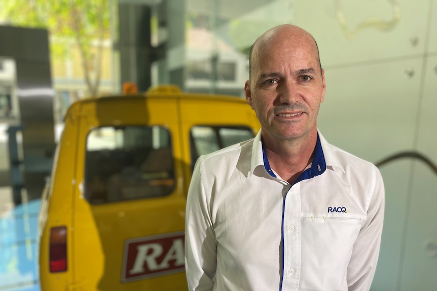 a man in a shirt button up shirt in front of a yellow van with racq on the back