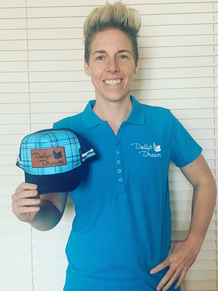 Elyse Villani smiles and holds a hat.