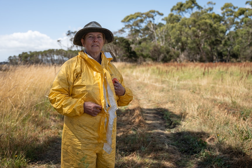 Woman in yellow hazmat suit stands for portrait