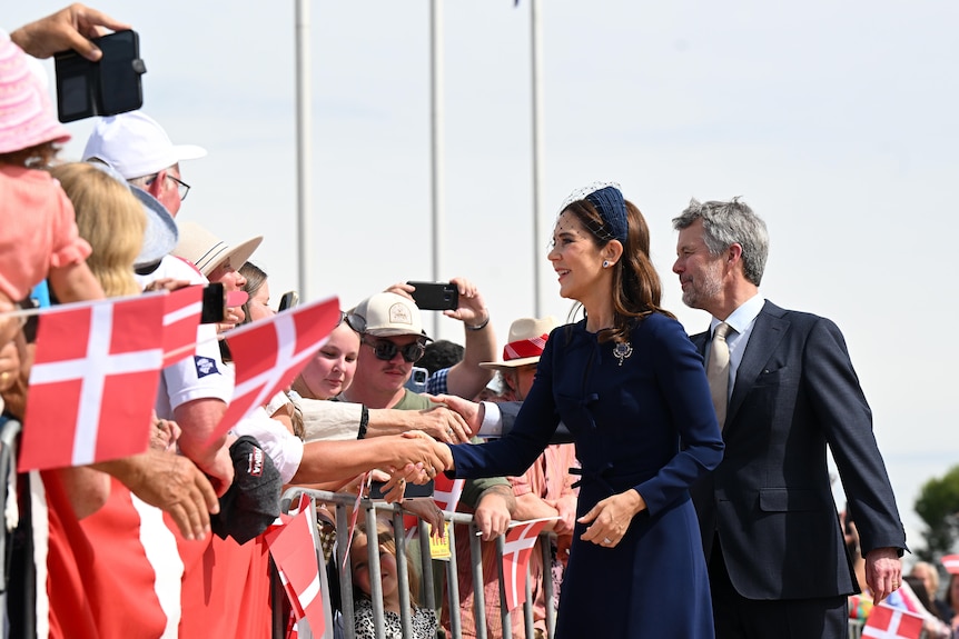 Queen Mary and King Frederik shaking hands with people. 