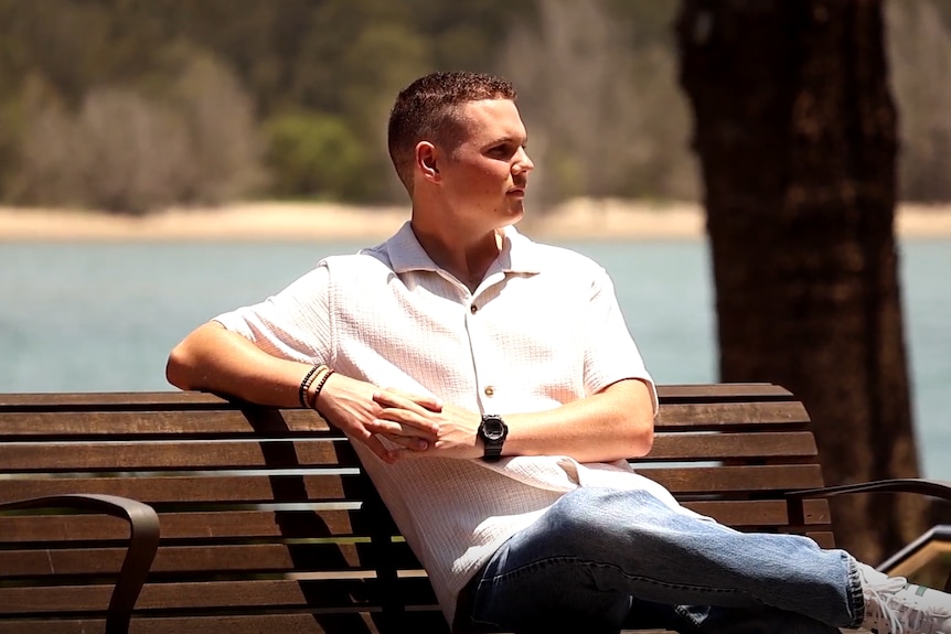 A man sits on a bench looking away from the camera.