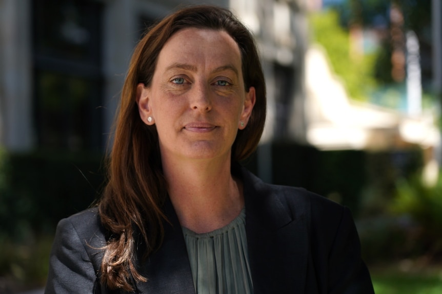 Jess Beckerling stands outdoors with a serious expression.