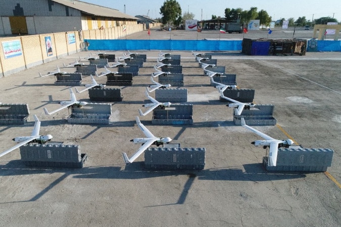A close up of rows of silver drones laid out on a concrete patch.