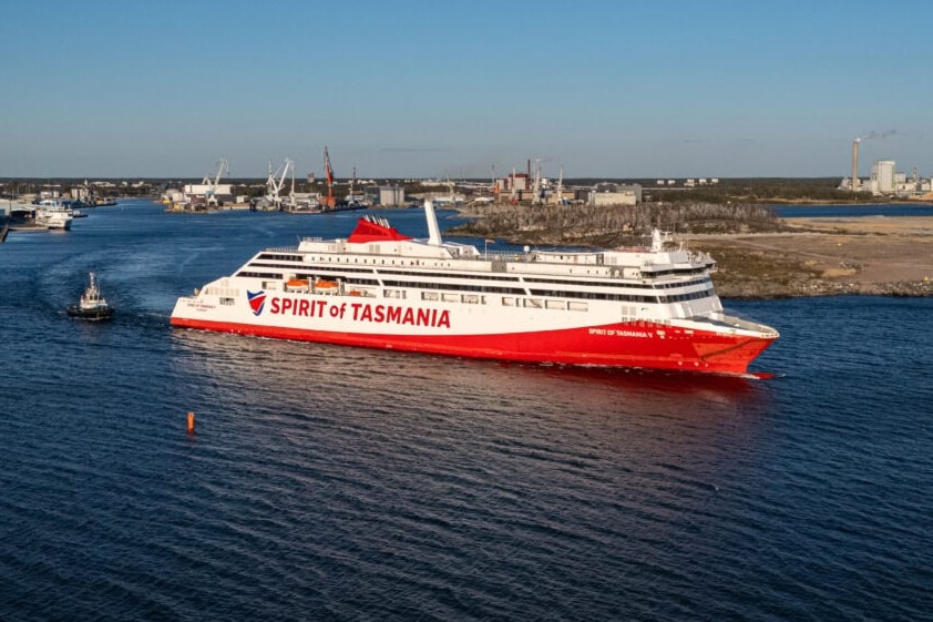 A large red and white ship pulls out of port.