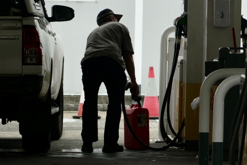 A motorist fills a jerry can at a service station. 