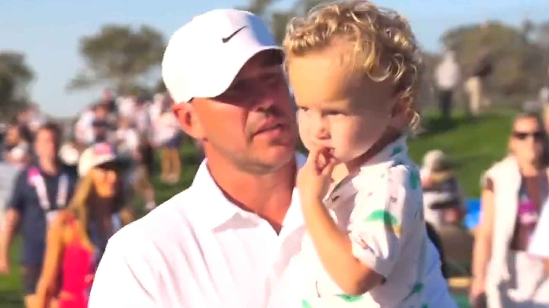 Brooks Koepka walks with his son, Crew, at the Farmers Insurance Open.