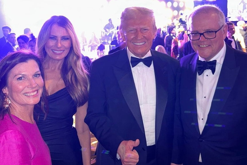 Two women and two men in formal attire smile at the camera.