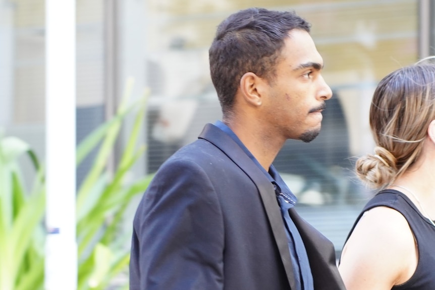 Roosevelt Williams Jr wears a suit as he walks along a street.