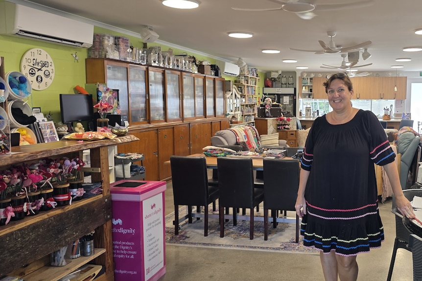 Lady in a black dress standing inside a large room full of craft supplies. 