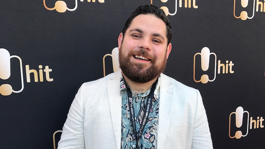 A man looking at the camera holding a microphone 