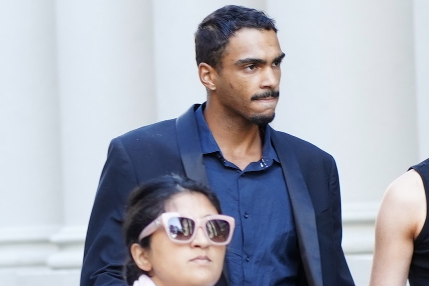 Roosevelt Williams Jr wears a suit as he walks along a street.