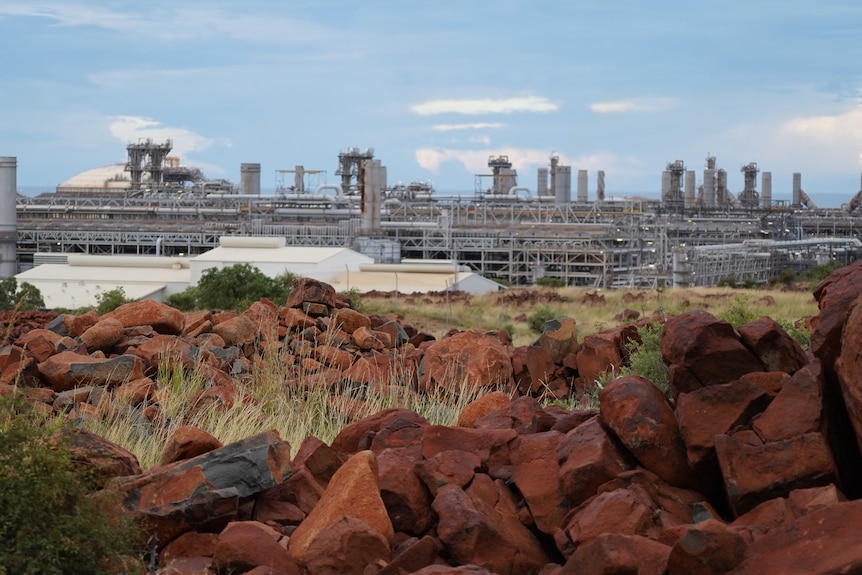 Close up of a collection of jagged red rocks. In the background, two towers spitting flames.