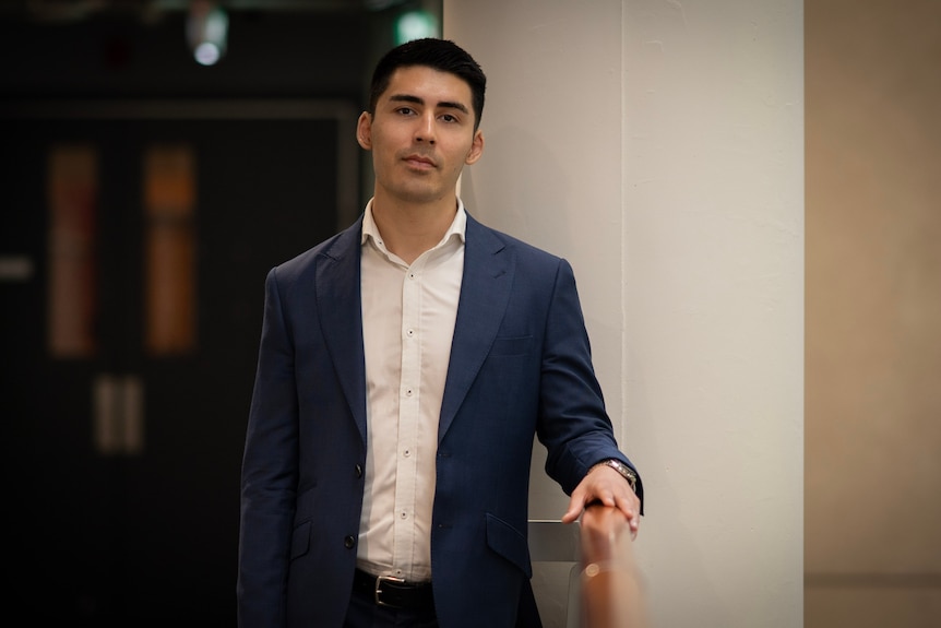 Solicitor Hayder Shkara leans on a railing in a hallway.