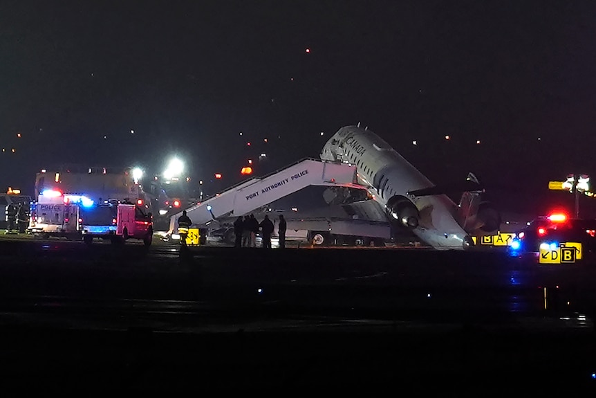 The nose of a plane on the ground with several vehicles surrounding it.