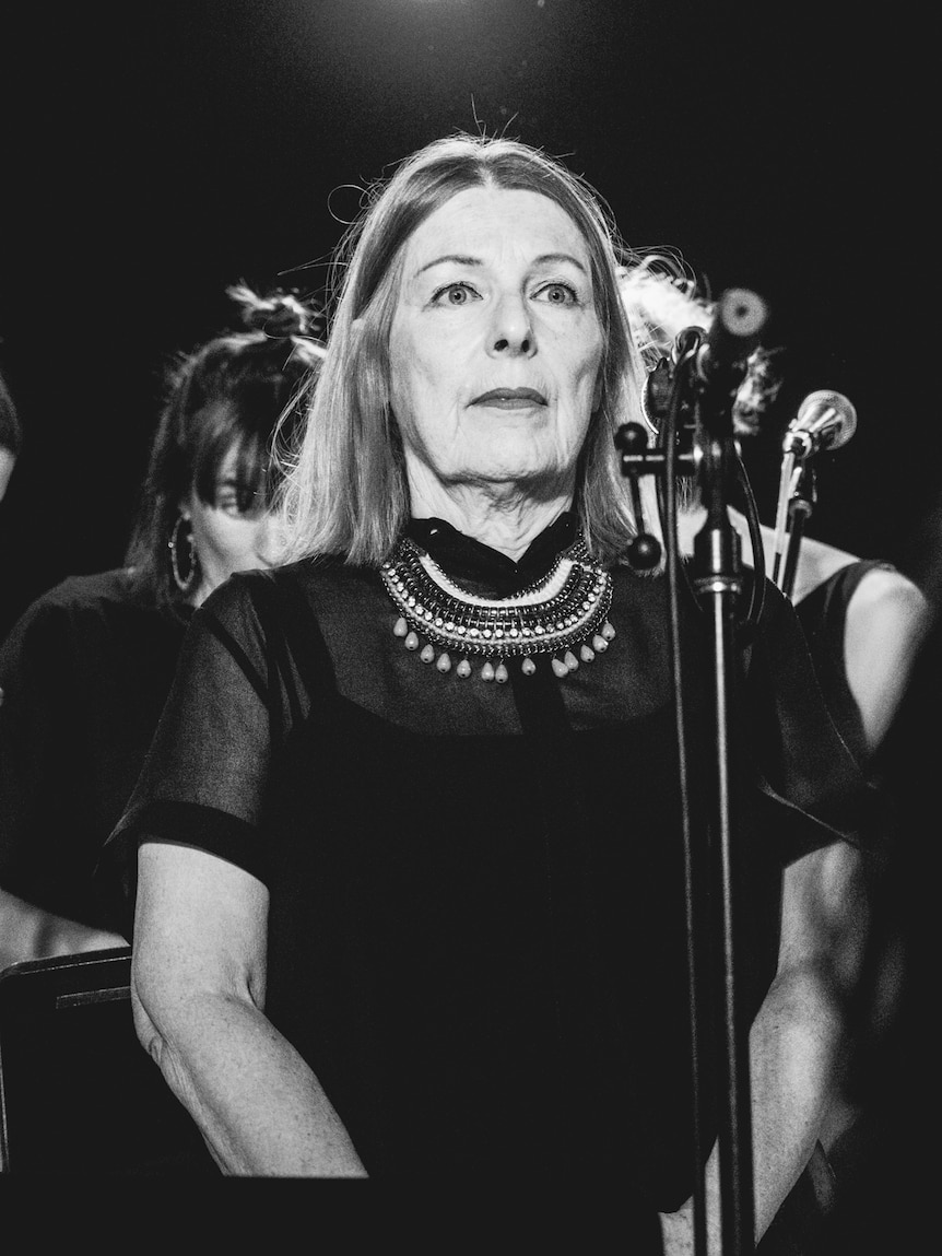 Black and white photo of woman standing at microphone on stage