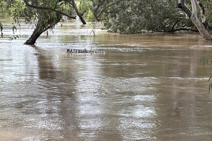 A sign for a river is barely visible under floodwaters.