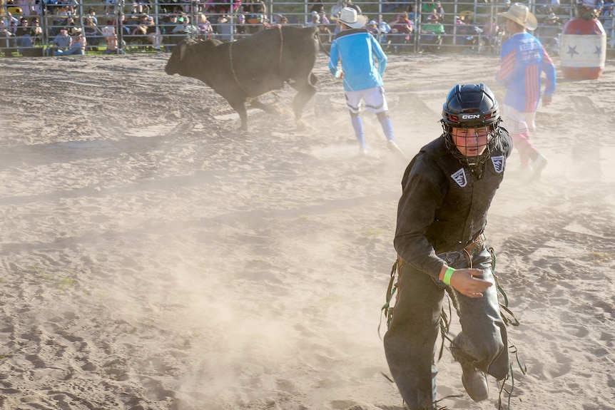 A man runs from a ball in a ring. 