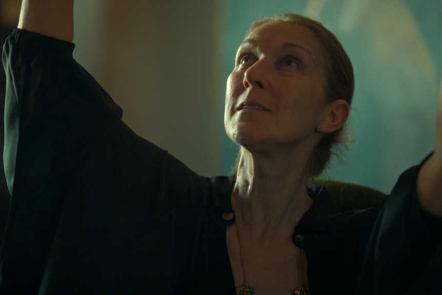 Celine Dion with arms up handing what appears to be a portrait