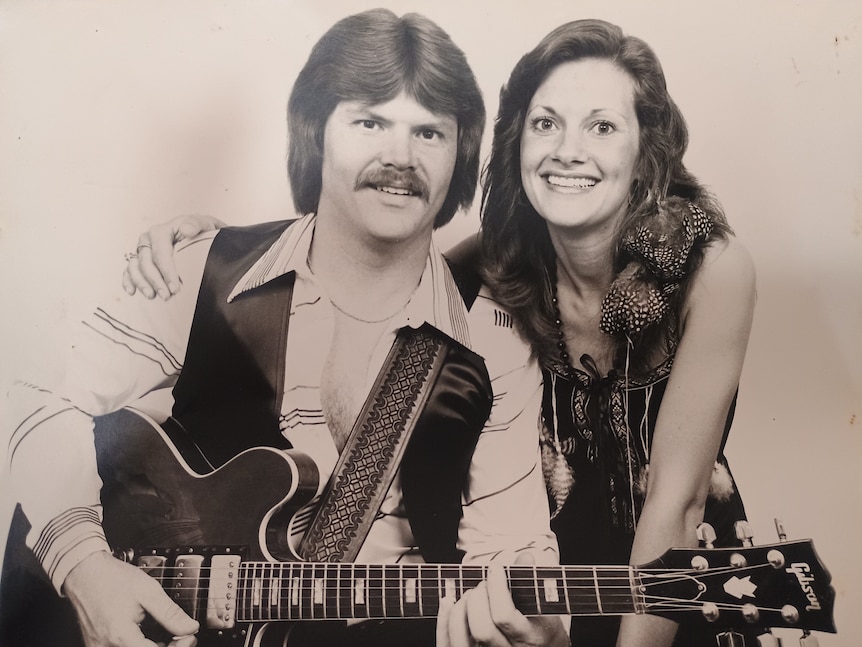 A black and white image of a man with guitar beside a woman.