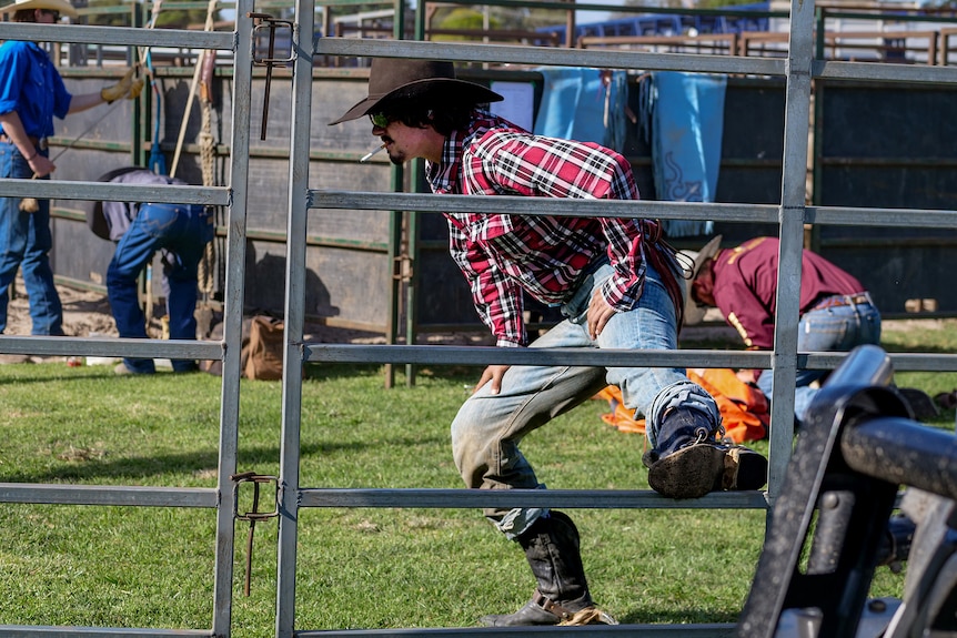 A man smoking a cigarette stretches.