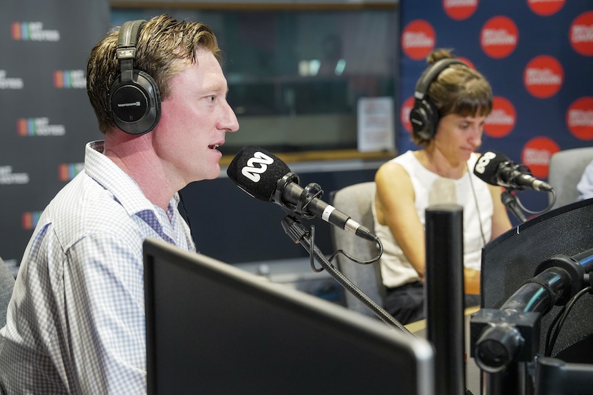 A man speaking into a microphone inside a radio studio.