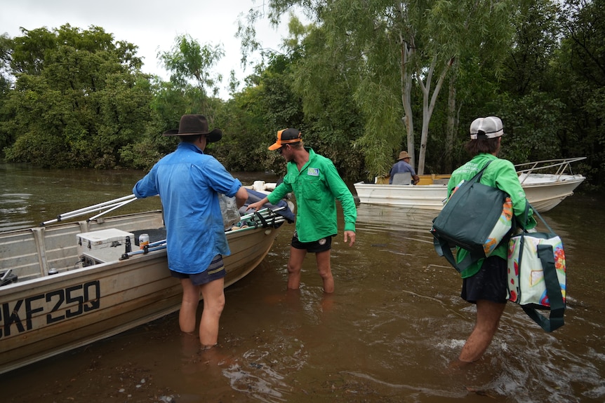 A group of people moving bags of groceries out of a tinny.