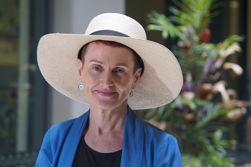A woman in a blue top and a wide-brimmed sun hat 