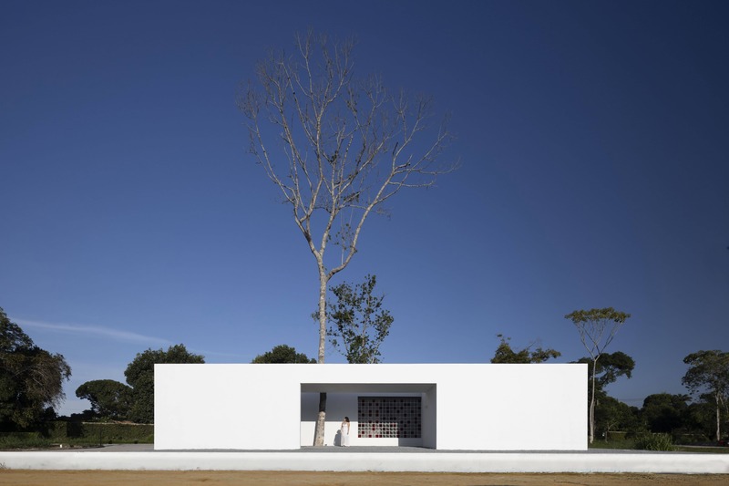 white perforated cubic facade wraps hybrid home and studio around a tree in brazil - 1