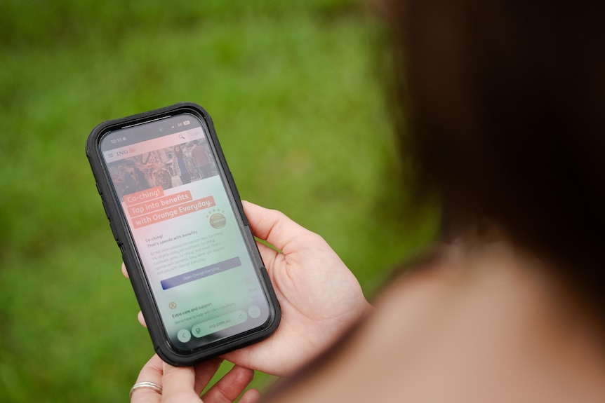 A woman looks at a banking app on her phone