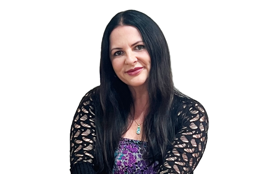 Susan with long black hear, black cardigan and purple dress smiling while sitting.