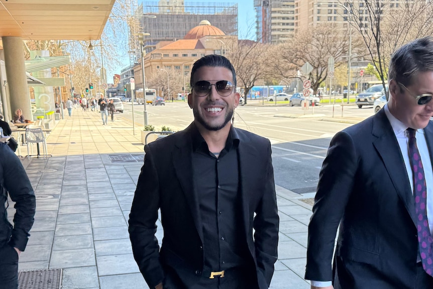 People in suit jackets outside court.