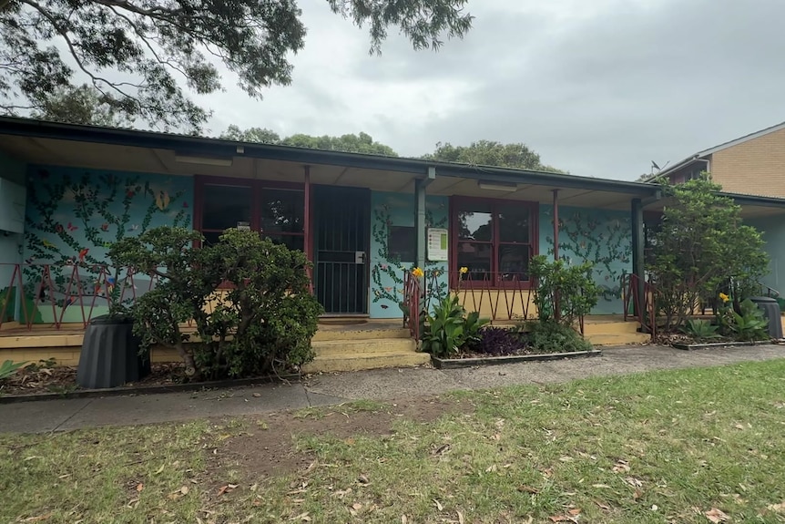 Fibro one-storey building covered in bright hand-drawn paintings