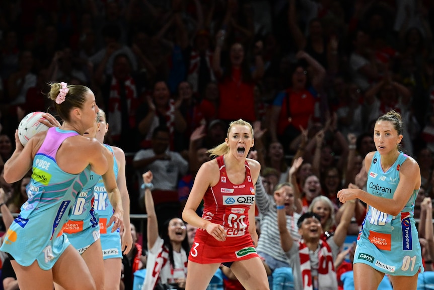 A player roars after scoring a goal in front of a crowd standing on their feet