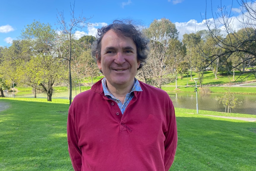 A man in a red top in a park near a river
