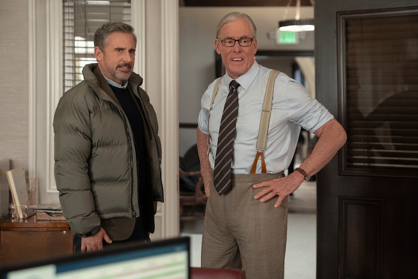 Two men stand in an office.