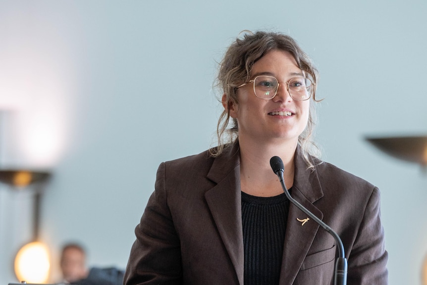 Sam is speaking in front of a microphone and stand at the strategy launch.