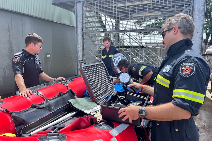 Men in QFD uniforms standing across a swift water rescue boat