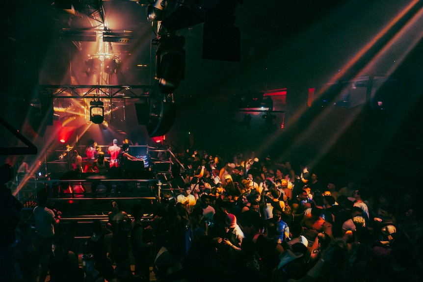 A crowd dancing next to a stage with a DJ